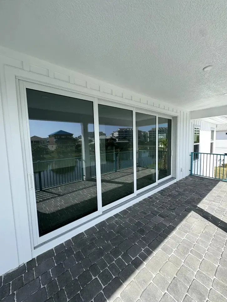 Four-panel white sliding glass door on a lakefront paver lanai, a finished Sunbright job